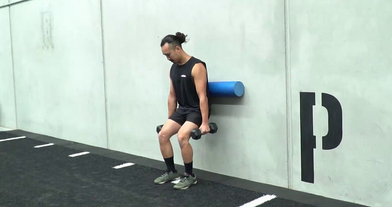 Performing Wall-Assisted Squats with foam roller